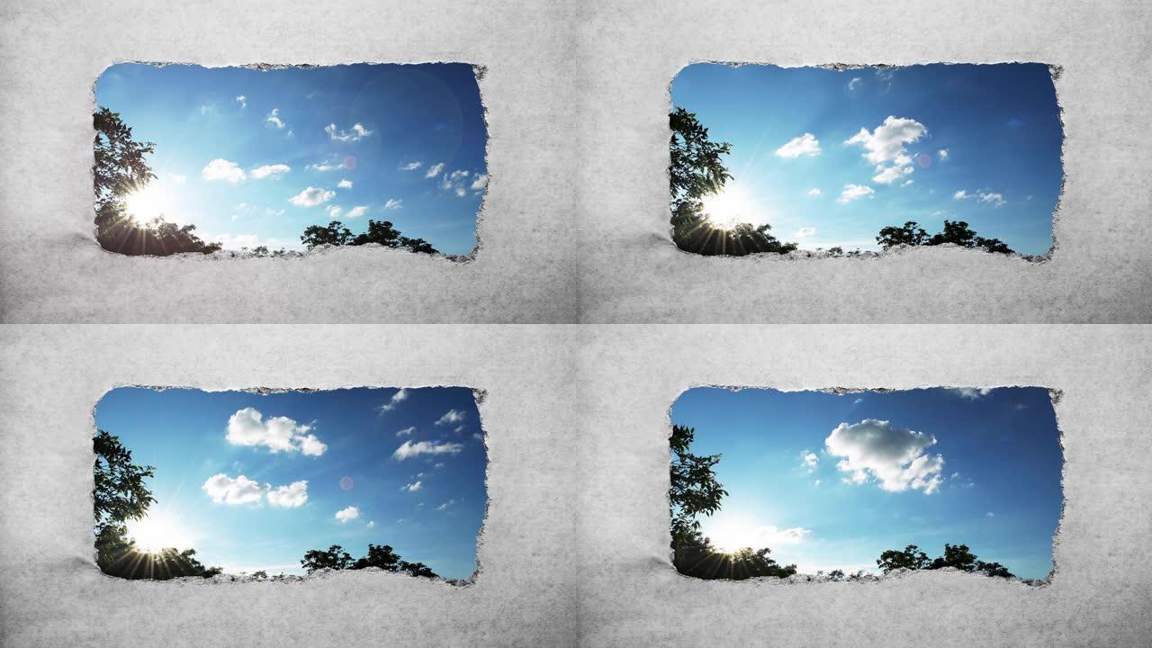 创意4k时间圈视频，在日落时分在蓝天中快速移动的云彩，这些云彩可以通过旧复古垃圾老式纸张边缘撕裂的孔