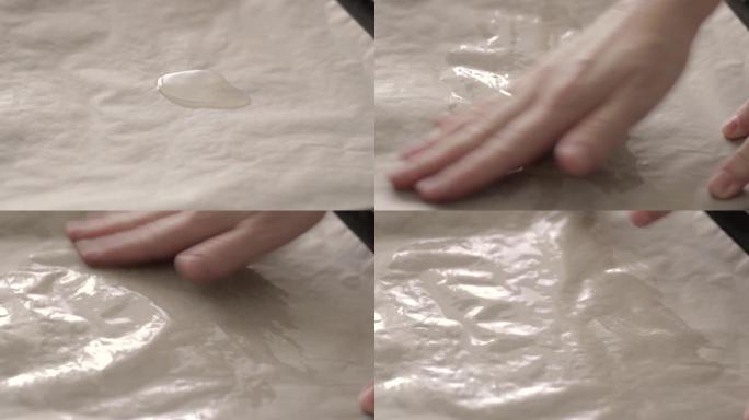 烤纸。一滴橄榄油。准备自制烘焙面包。女性手部涂片油