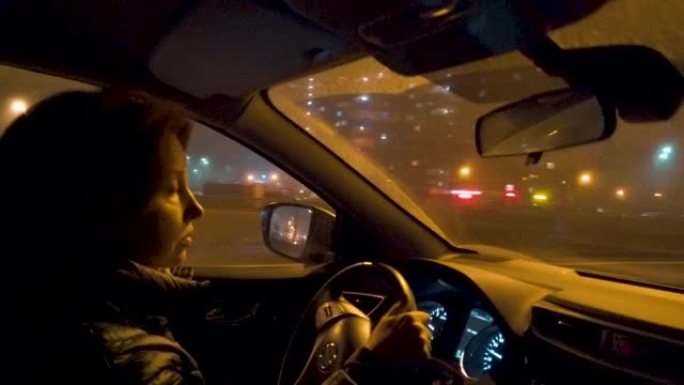 在夜城，一名妇女坐在汽车的方向盘后面