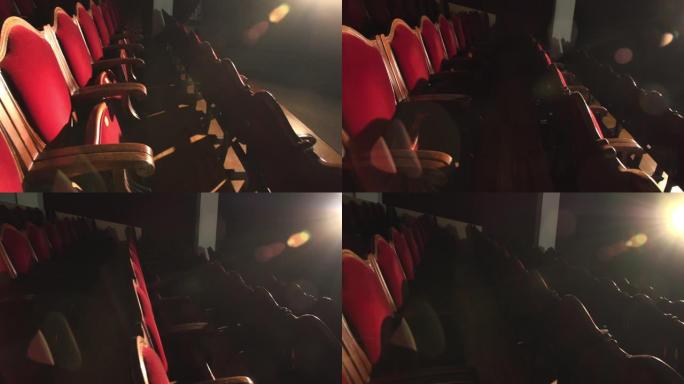 剧院椅子在空荡荡的剧院大厅里排着红色天鹅绒座椅，被聚光灯照亮。