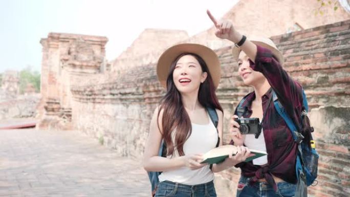 美丽的亚洲两个女人，拿着日记本和摄影胶片相机，她正在泰国世界遗产城市大城府享受。女人玩得开心，在老城