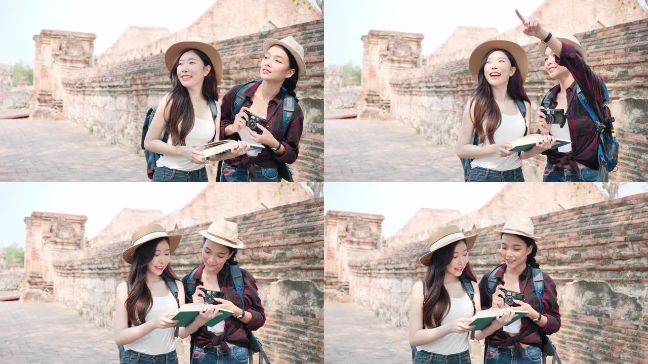 美丽的亚洲两个女人，拿着日记本和摄影胶片相机，她正在泰国世界遗产城市大城府享受。女人玩得开心，在老城