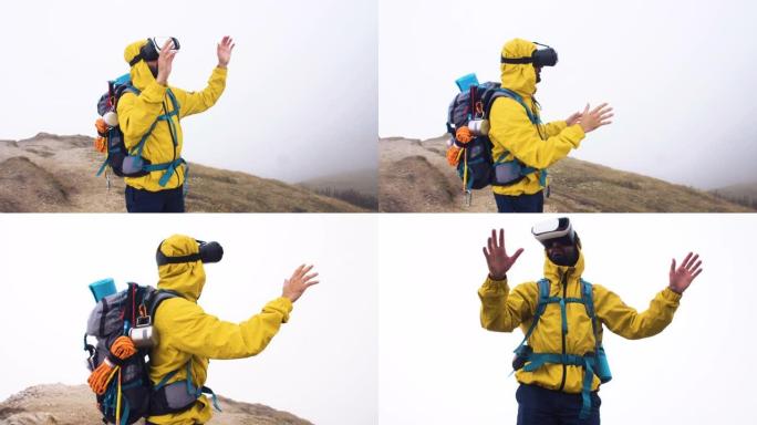 VR虚拟现实耳机。年轻的徒步旅行者在多云的天空和雾的背景下移动双手。山峰上的黄色兜帽夹克和背包。
