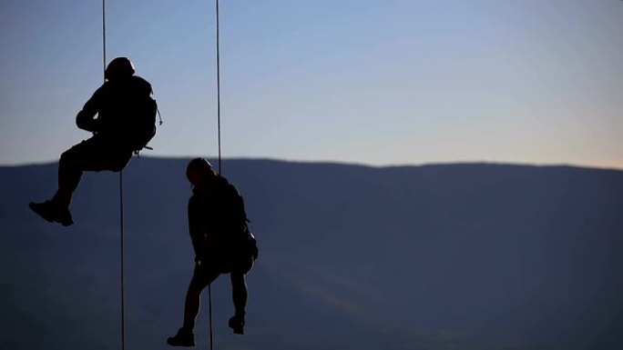 夫妻在绳子上用智能手机拍照。日落登顶的登山队