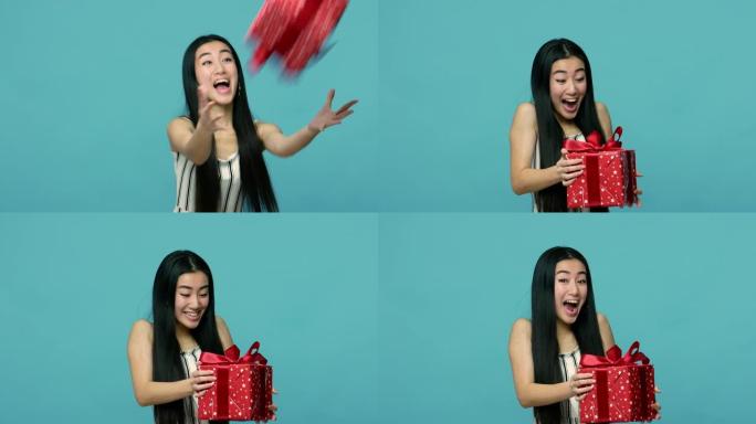 快乐的亚洲女人，留着黑色长发，抓着包裹的礼物盒子，看着相机高兴又惊讶