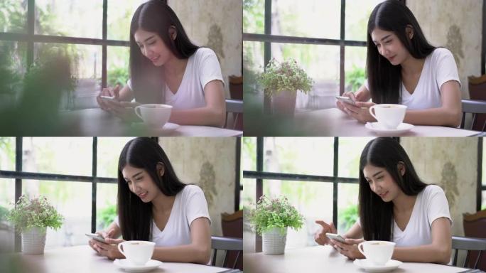 美丽的亚洲女人在咖啡馆使用智能手机。她使用智能手机以微笑和快乐的方式检查社交媒体。选择聚焦镜头