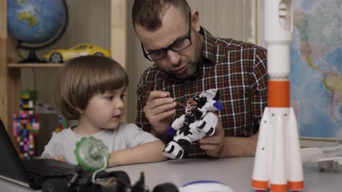 男孩和老师，在现代教室里组装机器人。爸爸带着小儿子在家组装机器人。教育科学，技术儿童，编程电子机器人
