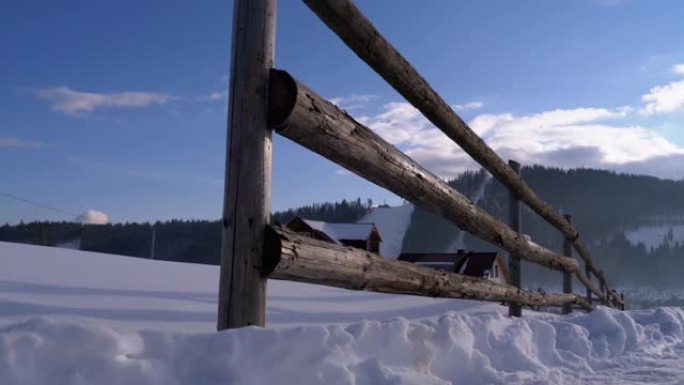 冬季农村景象，旧废弃木栅栏和白雪皑皑的木屋和山