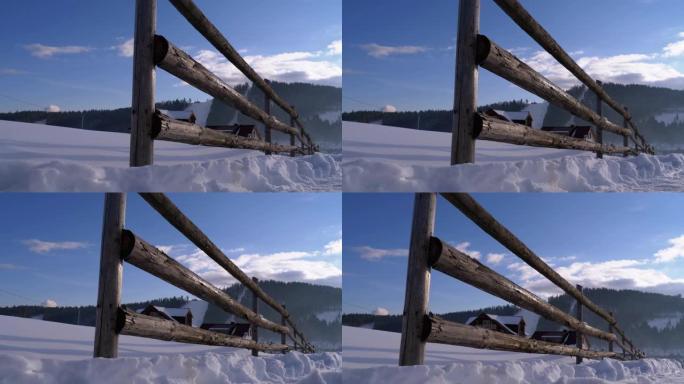 冬季农村景象，旧废弃木栅栏和白雪皑皑的木屋和山