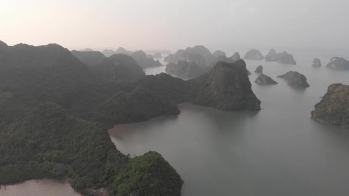 空中: 日落时分在越南著名旅游胜地下龙湾和猫巴岛上空的独特飞行。风景秀丽的天空有云，地平线上的石灰岩