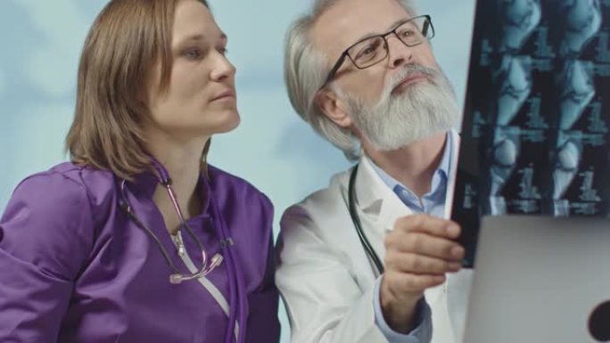 医生和一名护士正在看x光和ct扫描。电晕感染。中拍，4k慢动作