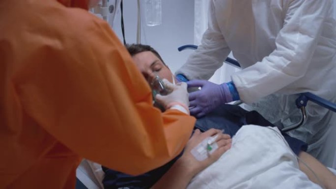 穿着防护服的医生给患有冠状病毒中针的病人戴上氧气面罩