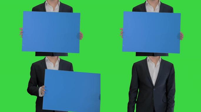 穿着西装的男人在绿色屏幕上拿着一块空白板，色键