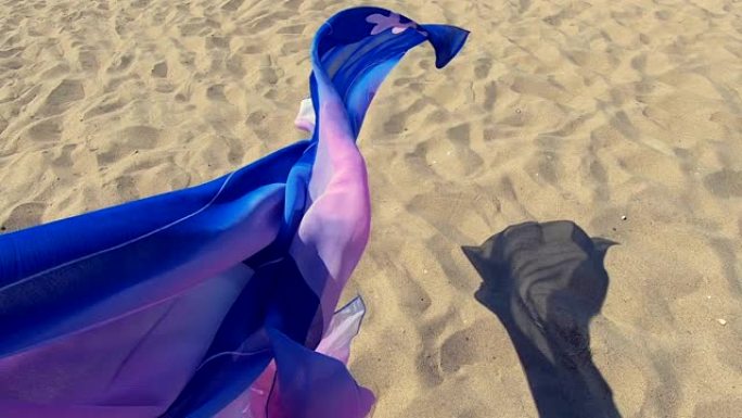 抽象的概念背景。围巾布在风中飘扬在沙滩上