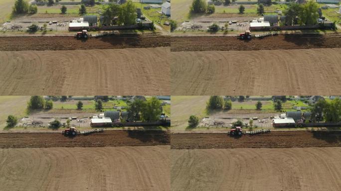 一位农民在红色拖拉机上的空中射击，用带支撑轮的反向犁处理农田