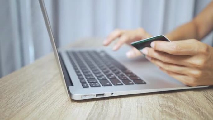 网上购物概念。女人手握信用卡并使用笔记本电脑