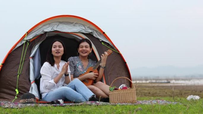 一群亚洲朋友在暑假玩Ukelele，花时间野餐。他们在假期很开心，玩得开心。他们用笔记本工作