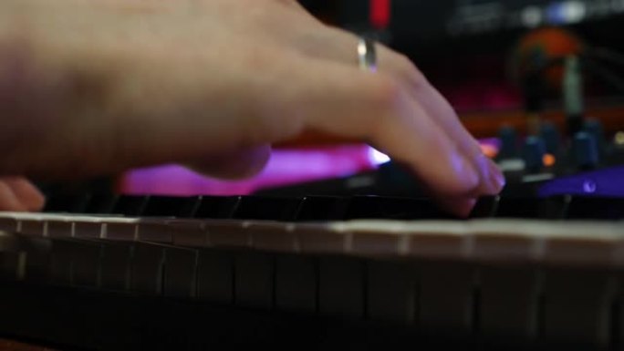 录制家庭工作室的男性手指在电钢琴上弹奏。近距离演奏钢琴midi键盘。录音师在家庭工作室创作音乐。音乐
