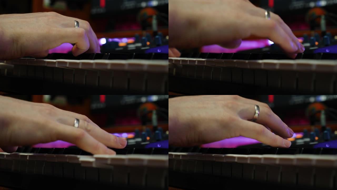 录制家庭工作室的男性手指在电钢琴上弹奏。近距离演奏钢琴midi键盘。录音师在家庭工作室创作音乐。音乐