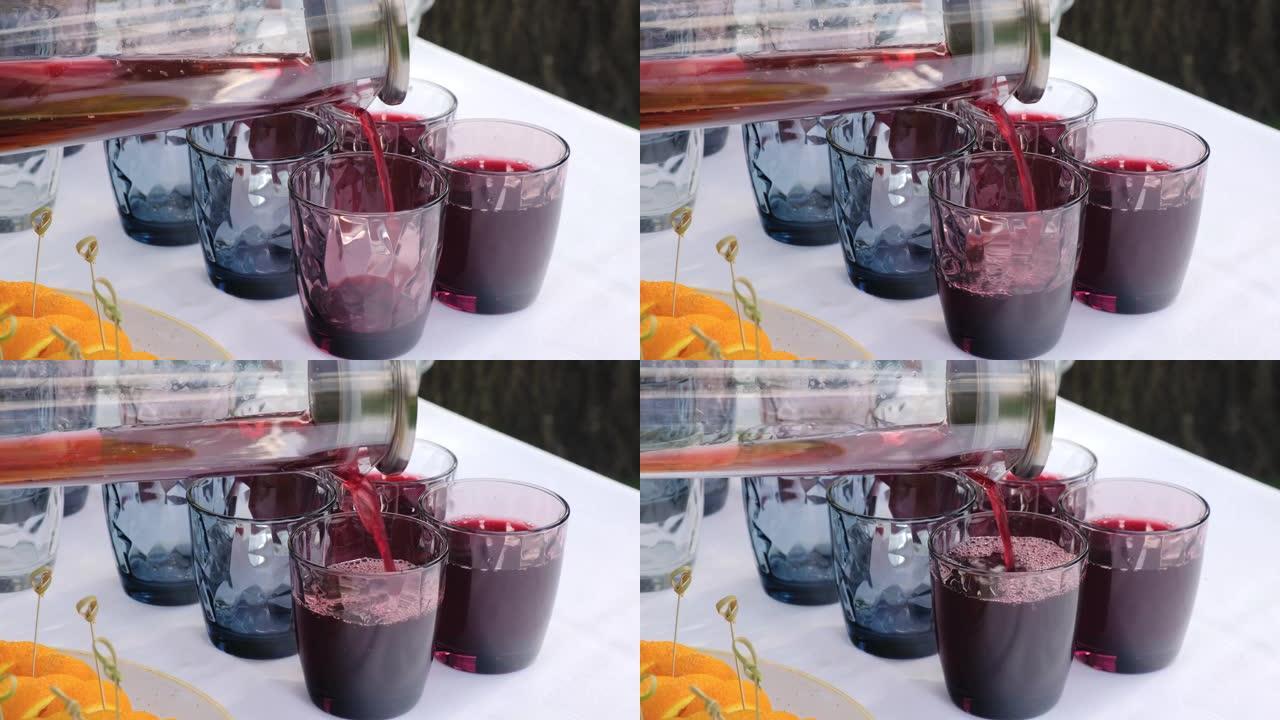 服务员在宴会上把果汁倒入玻璃杯中。特写视图。