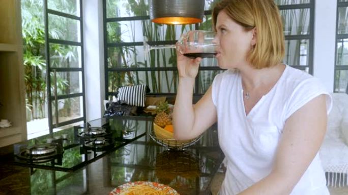 悲伤沮丧的女人在现代家中喝酒时独自吃饭