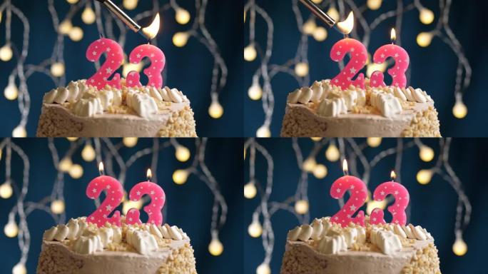 蓝色背景上有23号粉色蜡烛的生日蛋糕。蜡烛着火了。慢动作和特写视图