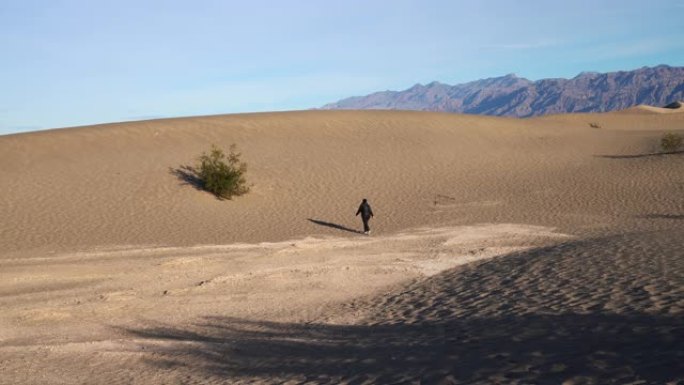 女人在加利福尼亚州死亡谷的梅斯基尔公寓的沙丘上徒步旅行。