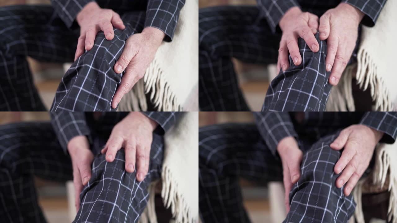成熟男性白人双手在睡衣中摩擦膝盖的特写。遭受痛苦的高级退休人员。生活方式，老龄化，健康问题