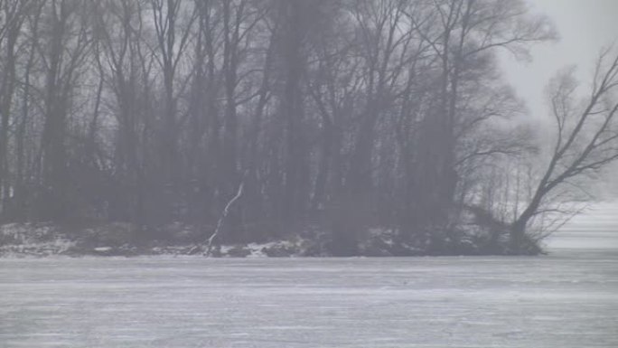 渔民在被雪覆盖的小而自然的冰冻冬季湖上。太阳落山雾气升起，湖上的冰钓冬季风光