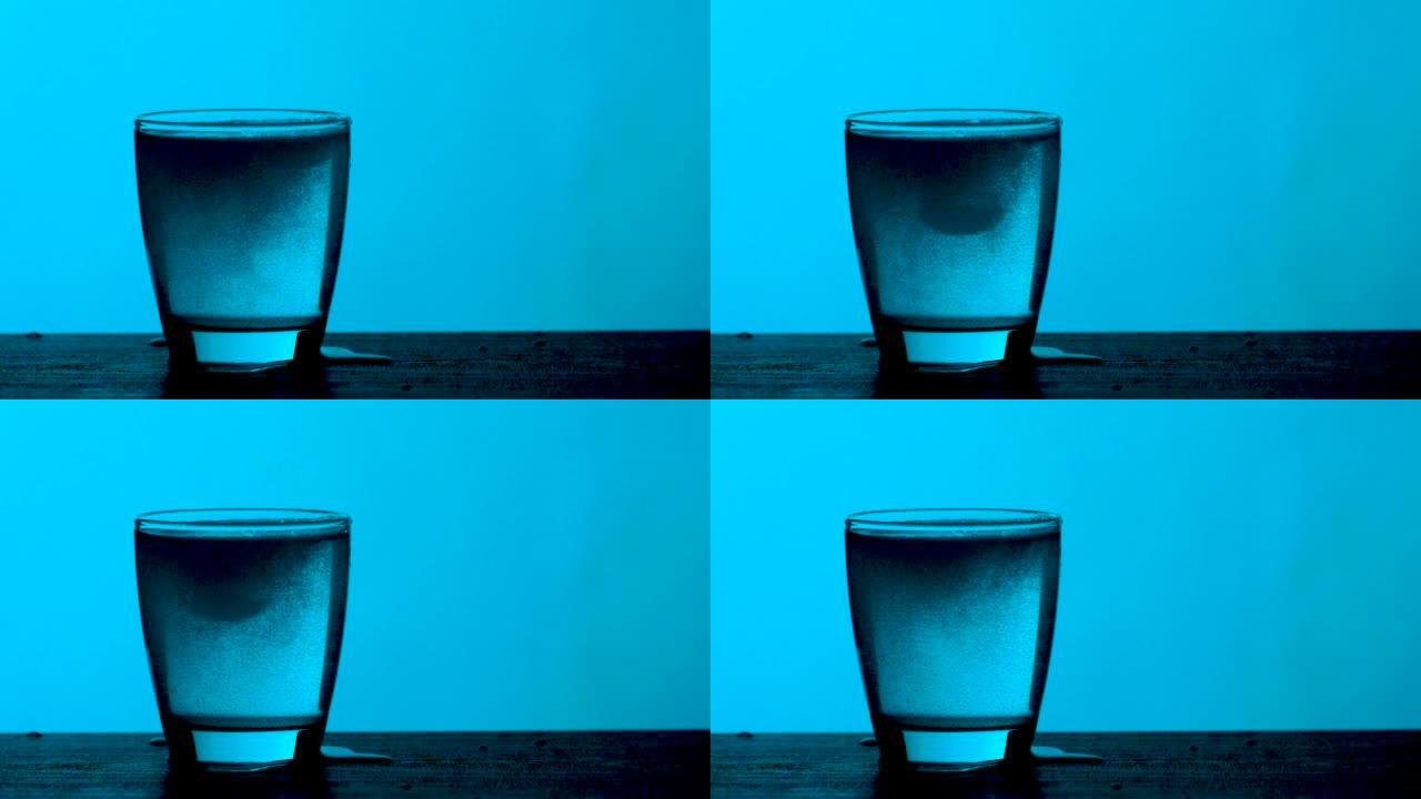 泡腾片滴入一杯水蓝色背景，慢动作