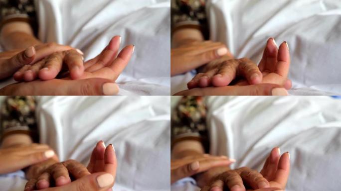 女人牵着躺在床上的老母亲的手。孙女温柔地抚摸奶奶的手给予支持。女儿在诊所安慰年迈妈妈的皱纹。关心或爱
