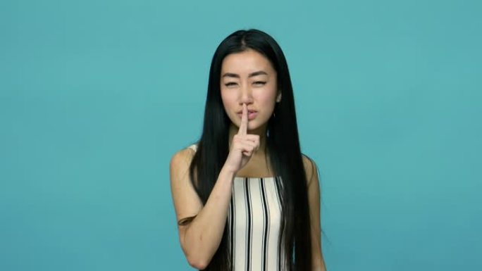 嘘，保持沉默!严肃的亚洲女性，留着长长的直发，用严肃的脸打手势安静