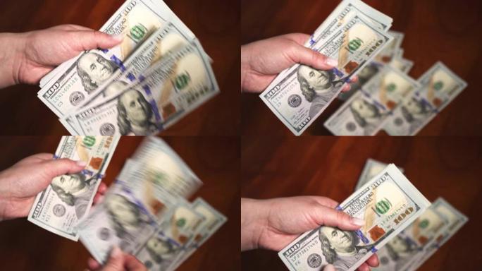 100美元的钞票在女性手中。数数，数钱。财富。很多钱。