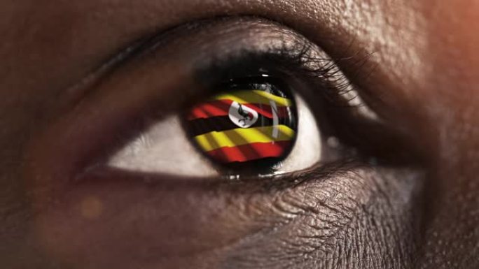 妇女黑眼睛在近距离与旗帜乌干达在虹膜与风运动。视频的概念