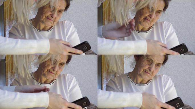 一位年轻女子向祖母展示了如何使用智能手机，她将其握在手中，并告诉一位老年妇女。