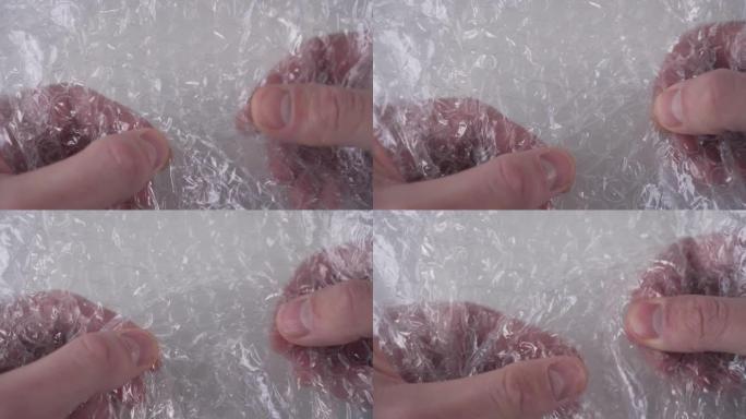 那家伙用手指按压包装塑料胶带的气泡，它们破裂了