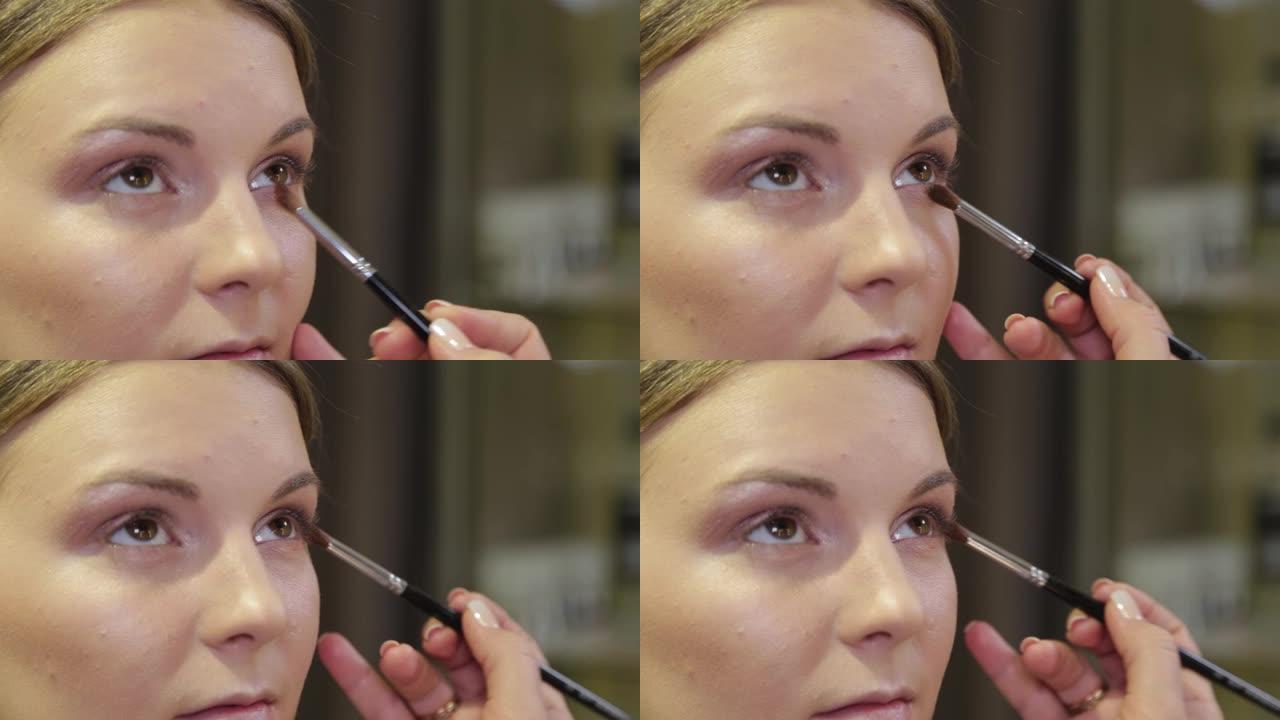 专业化妆师用刷子给美容院的客户涂眼影