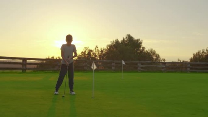 日落时打高尔夫球的男孩