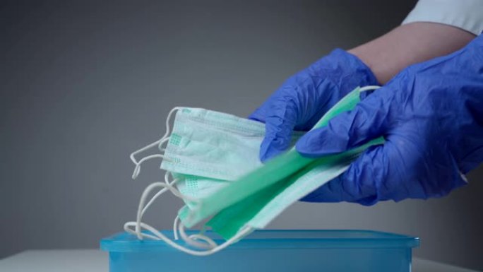 医生或护士从塑料容器中取出呼吸面罩。用医用手套保护的手。大流行保险冠状病毒，新型冠状病毒肺炎，传染性