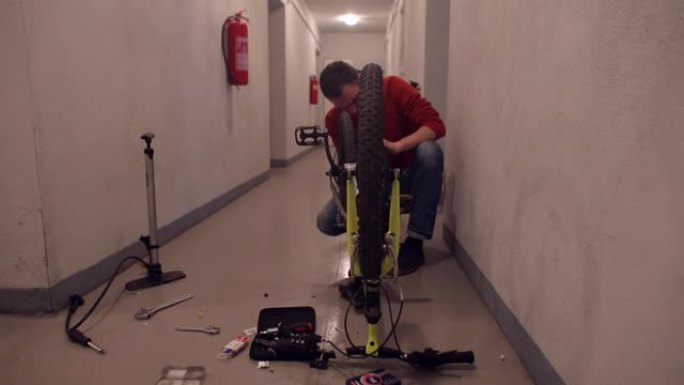 一名男子在公寓楼的地下室修理自行车。
