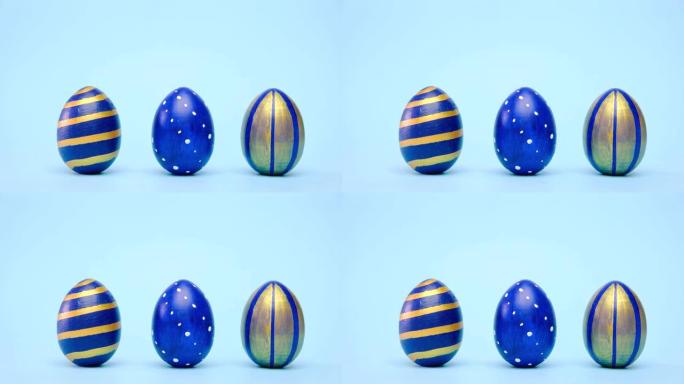 复活节彩蛋在滚动，互相敲在蓝色的桌子上。鸡蛋时尚彩色经典蓝色、白色和金色。复活节快乐。最小风格