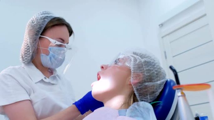 牙医在超声波清洗期间将棉塞放在女性口腔干牙中。