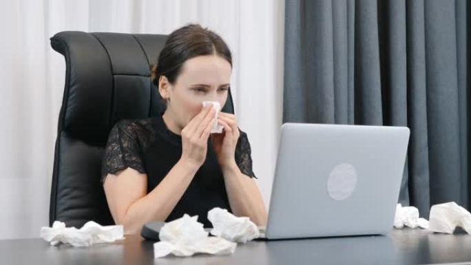 办公室流鼻涕的女人。女性坐在办公桌前擦鼻子。流鼻涕的女商人在办公室工作。手拿餐巾纸在笔记本电脑上工作