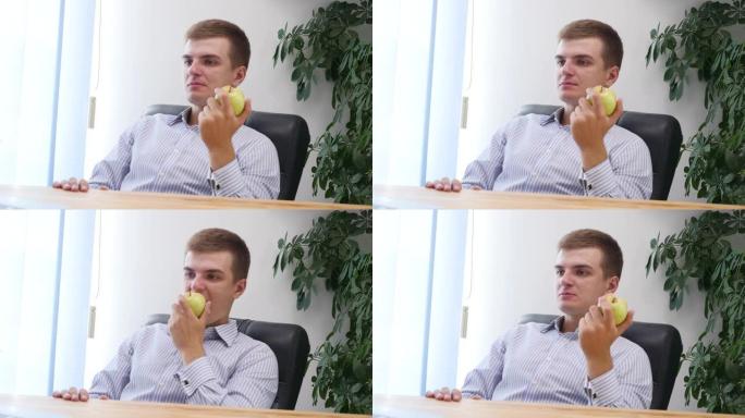 年轻的商人正在办公室里吃苹果。特写。复制空间。4K。