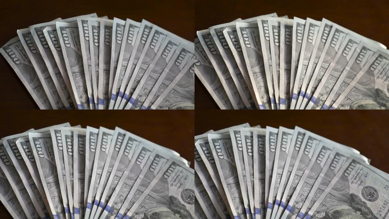 一位商人的特写镜头在桌上数着百美元的钞票