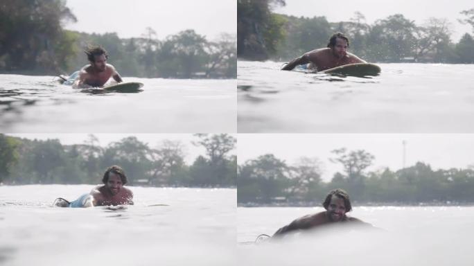 印度尼西亚爪哇，帅哥在冲浪板上划水向相机游泳的特写镜头