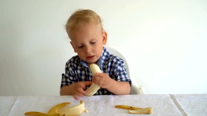 英俊的蹒跚学步的孩子正在吃黄色香蕉。万向节运动镜头