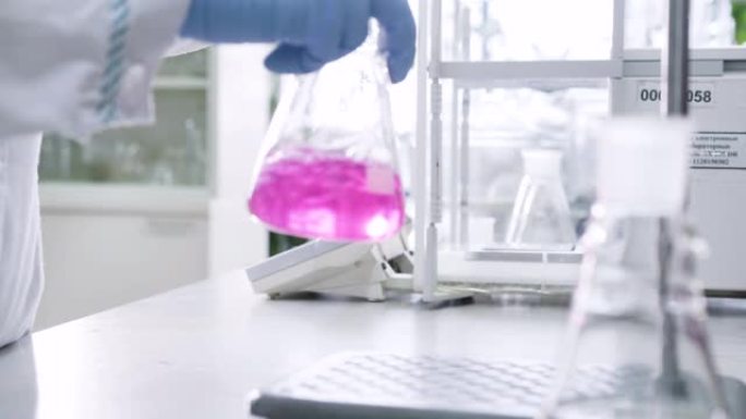 化学家摇动液体和粉红色化学物质变得清晰