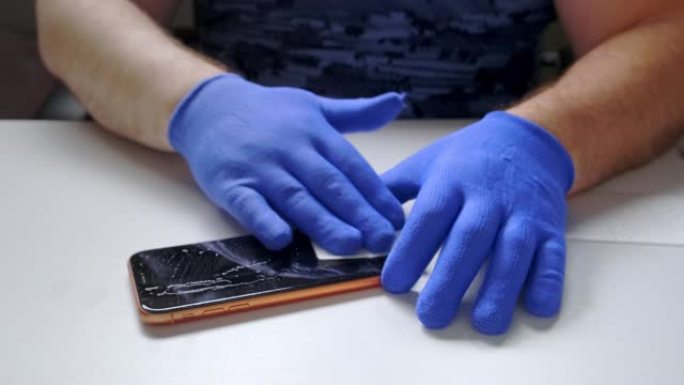 男性的手代替了智能手机的钢化玻璃屏幕保护膜。