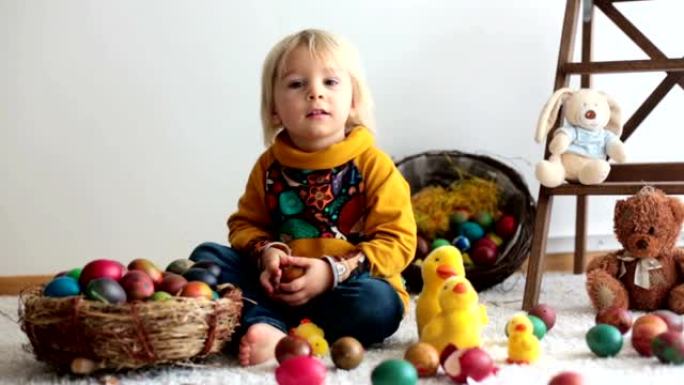 蹒跚学步的孩子，玩复活节彩蛋的金发男孩。孩子们玩鸡蛋和小鸡